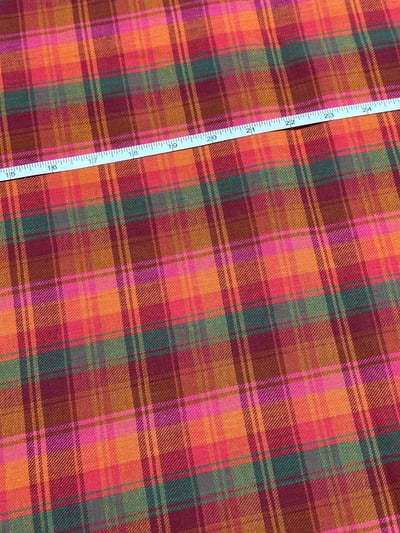 Orange, maroon, pink, red and green twill madras check yarn-dyed fabric, with bright pink bands and fine yellow lines.